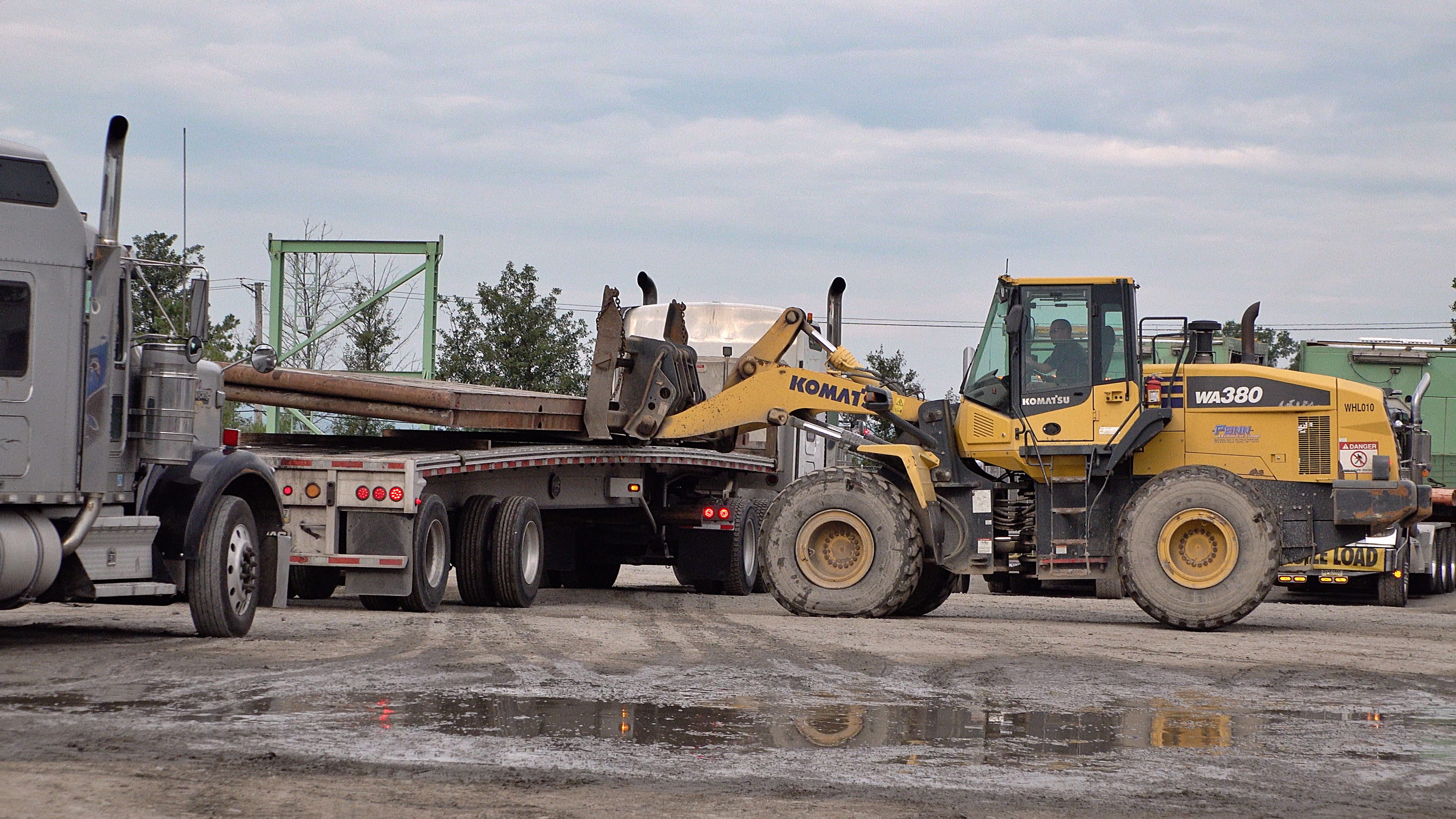 Heavy components are listed onto flatbed trucks for removal from the CUBO site.